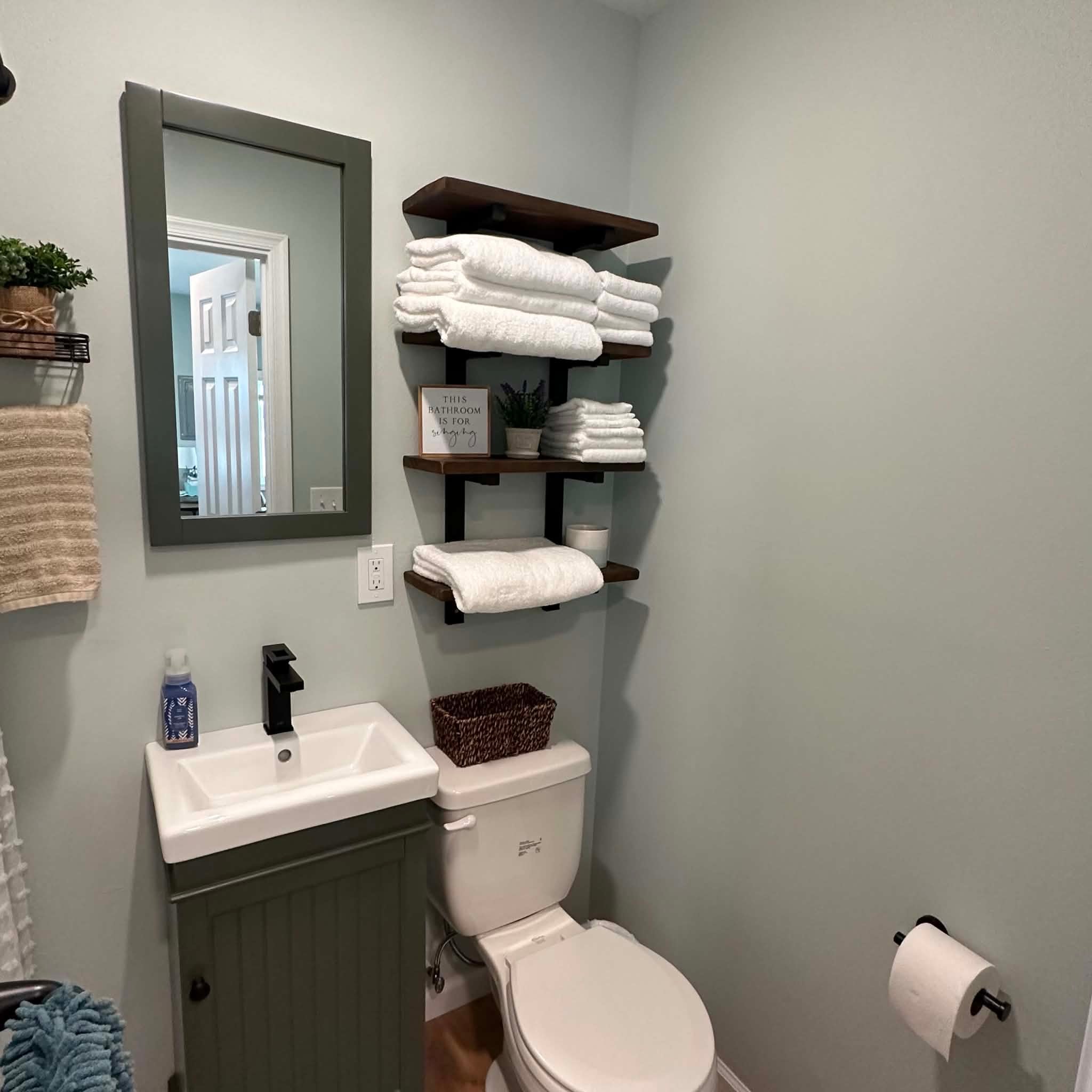Guest bathroom with a gray vanity, mirror, and neatly folded towels