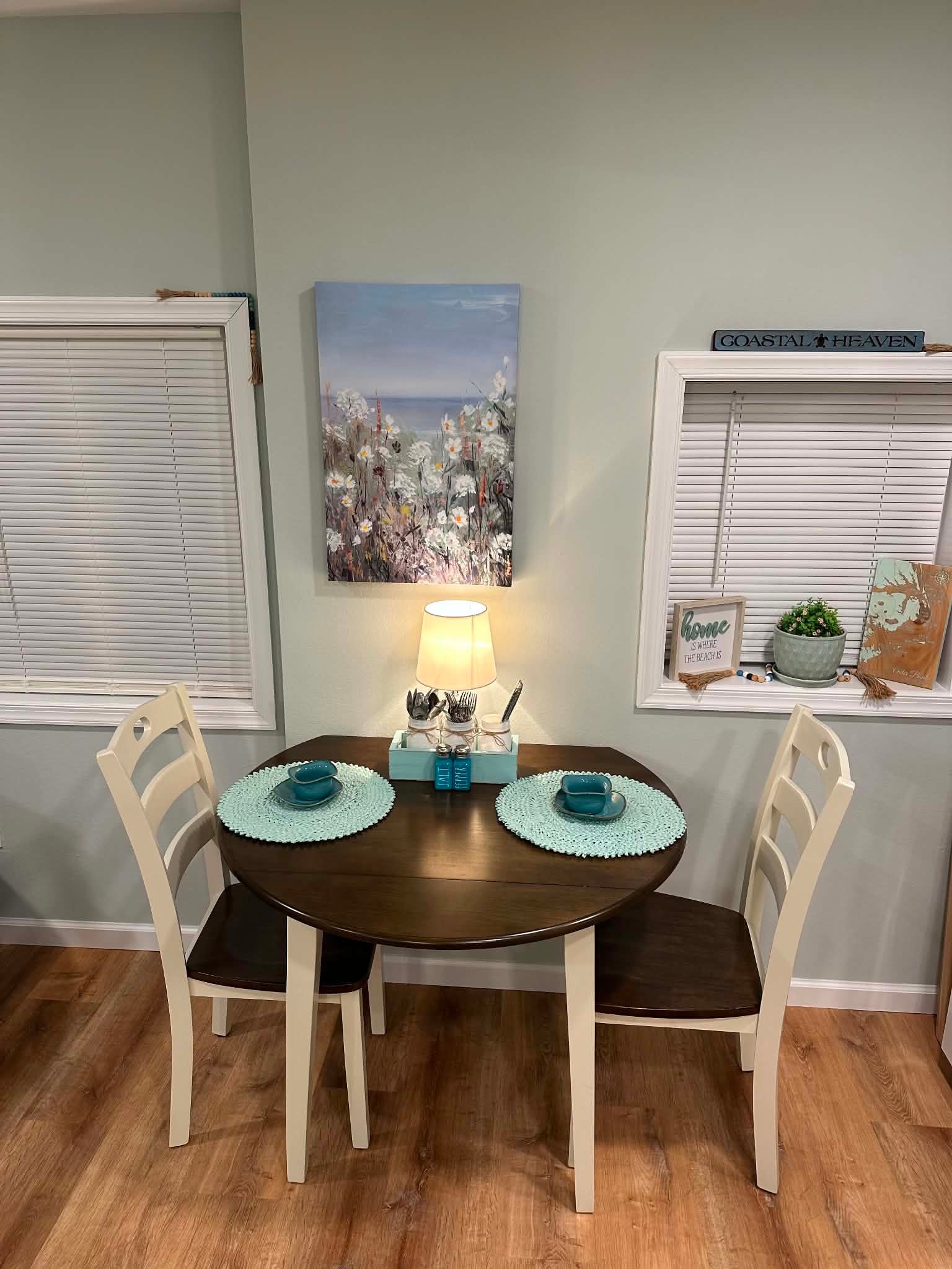 Coastal dining nook with aqua place settings and beach-inspired artwork