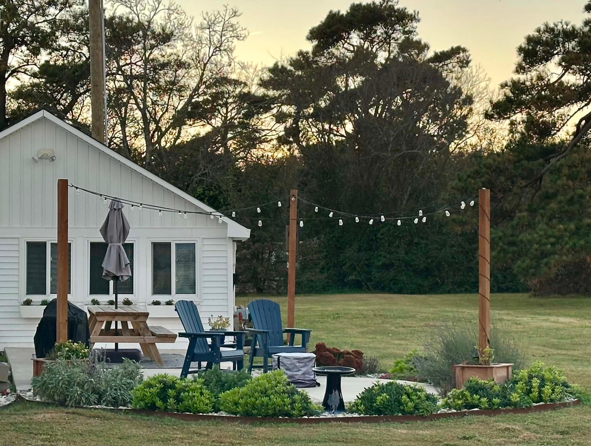 Guesthouse patio with Adirondack chairs and string lights at dusk