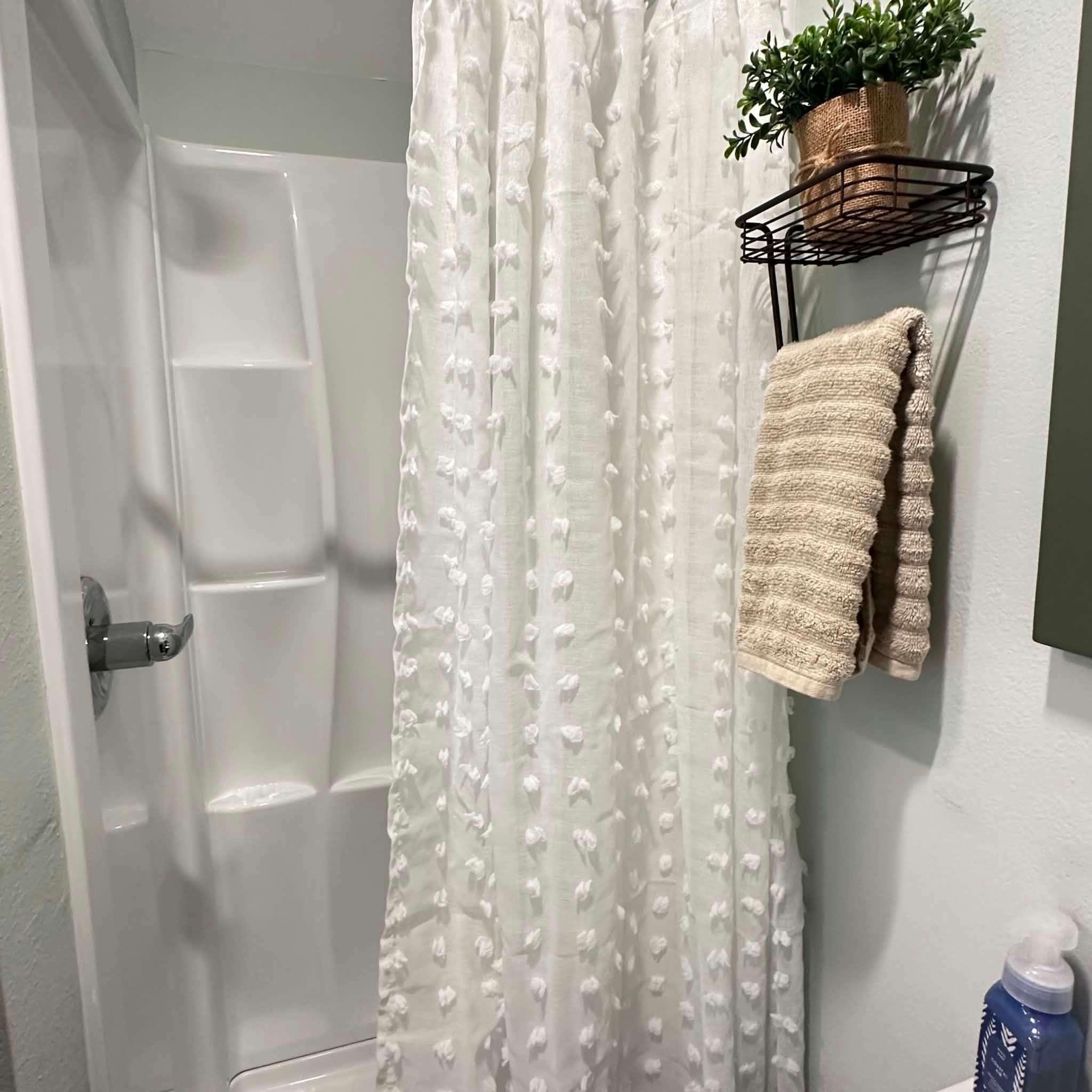 Guest shower with a textured white curtain and fresh towels